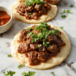 A steaming plate of carne guisada featuring tender chunks of beef in rich, savory gravy garnished with fresh cilantro, served alongside fluffy rice with a colorful medley of cooked vegetables, all presented on a rustic wooden table with warm natural lighting highlighting the glossy sauce and textured ingredients.