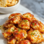 Colorful plated honey garlic chicken featuring tender chicken pieces glazed with glossy honey and garlic sauce, garnished with fresh herbs, with a vibrant background of vegetables and a rustic wooden table surface.